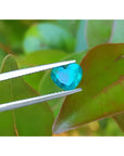 1.26 ct. vibrant bluish-green heart-cut Colombian emerald held by tweezers.