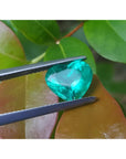 2.54 carat GIA certified heart cut Colombian emerald, sparkling bluish-green, held by tweezers.