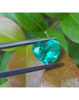 GIA certified 2.54 carat heart-cut Colombian emerald, sparkling bluish-green, held by tweezers.