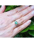 Heart-cut emerald engagement ring with diamond halo on a 14K yellow gold band, worn on a hand.