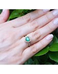 Heart-cut emerald engagement ring with diamond halo on a 14K yellow gold band, worn on a hand.