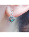 Emerald heart earring made of 14k gold worn on a woman's ear.