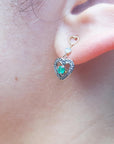 Close-up of a woman's ear wearing a natural emerald heart earring.