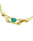 14K yellow gold Claddagh necklace with two hands holding a heart-cut emerald.
