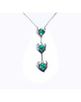 14K white gold journey pendant necklace with three heart-shaped settings, each holding a round emerald.