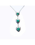 14K white gold journey pendant necklace with three heart-shaped settings, each holding a round emerald.