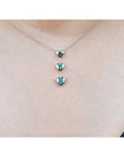 14K white gold heart emerald journey pendant necklace with three round-cut Colombian emeralds.