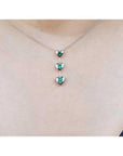 14K white gold heart emerald journey pendant necklace with three round-cut Colombian emeralds.