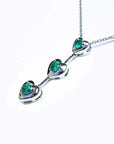 White gold necklace with natural emeralds heart-shaped stones on a white background