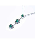 White gold necklace with natural emeralds heart-shaped stones on a white background