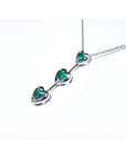 14K white gold heart journey pendant necklace with three round Colombian emeralds.