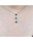 14K white gold heart emerald journey pendant necklace with three round-cut Colombian emeralds.