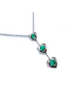 Three hearts emerald journey pendant necklace in 14k white gold topside view.