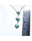14K white gold heart journey pendant necklace with three round-cut Colombian emeralds.
