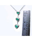 14K white gold heart journey pendant necklace with three round-cut Colombian emeralds.