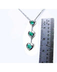 14K white gold heart journey pendant necklace with three round-cut Colombian emeralds.
