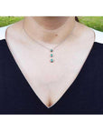 Heart emerald journey pendant necklace in 14K white gold, worn on a woman's neck.