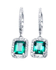 Pair of emerald hoop earrings with diamond accents on a front position, top view.