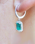 A left side profile of a 14k white gold emerald and diamond hoop earring worn on an ear.