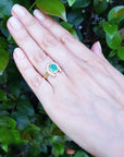 A hand wearing a horseshoe emerald ring for women crafted in 14k yellow gold