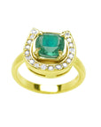 This yellow gold ring showcases a cushion-cut emerald set at the center of a horseshoe-shaped diamond design.