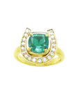 This horseshoe emerald ring displays a cushion-cut emerald framed by a semicircle of diamonds, in yellow gold.