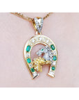 18K yellow gold horseshoe pendant with emeralds, diamonds, and a silver horse head.