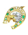 18K yellow gold horseshoe pendant with emeralds, diamonds, and two horse heads, one gold, one silver.