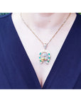 Necklace with a horseshoe emerald and diamond pendant on a person wearing a blue top.