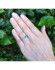 14K white gold ring with a bezel-set 0.73 ct emerald and accent diamonds on a hand.
