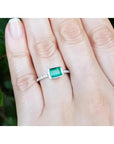 0.73 ct bezel-set emerald ring with accent diamonds on a 14K white gold band worn on a hand.