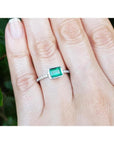 0.73 ct bezel-set emerald ring with accent diamonds on a 14K white gold band worn on a hand.