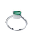 14K white gold ring with a bezel-set emerald and prong-set accent diamonds.