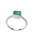 14K white gold ring with a bezel-set emerald and prong-set accent diamonds.