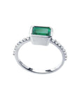 14K white gold ring with a bezel-set emerald and prong-set accent diamonds.