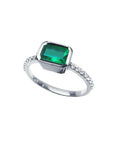 14K white gold ring with a bezel-set emerald and prong-set accent diamonds.