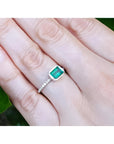 Hand wearing a bezel set emerald ring for women in 14k white gold