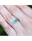 Hand wearing a bezel set emerald ring for women in 14k white gold