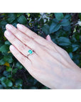 Emerald cut emerald engagement ring with diamond halo in 14K white gold on a hand.