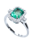 This affordable emerald engagement ring with a halo diamond in a tilted position shows the top ans side profile.
