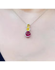 14K white gold ruby journey pendant with round ruby, two yellow sapphires, and diamond accents.
