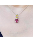 14K white gold ruby journey pendant with round ruby, two yellow sapphires, and diamond accents.