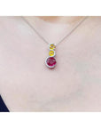 14K white gold ruby journey pendant with round ruby, two yellow sapphires, and diamond accents.