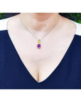 14K white gold journey pendant with a round ruby, two yellow sapphires, and diamonds on a woman's neck.