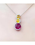 14K white gold journey pendant with a round ruby, two yellow sapphires, and diamond accents on a chain.