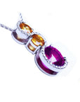 14K white gold ruby journey pendant with two yellow sapphires and diamond accents.