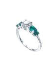 14K white gold ring with a round diamond center and four side emeralds.