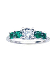 A women's round cut natural diamond ring with side colombian emeralds crafted in 14k white gold.