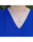 Ethiopian Welo opal and diamond pendant in 14K white gold, worn on a woman's neck.