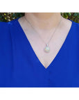 Ethiopian Welo opal and diamond pendant in 14K white gold, worn on a woman's neck.